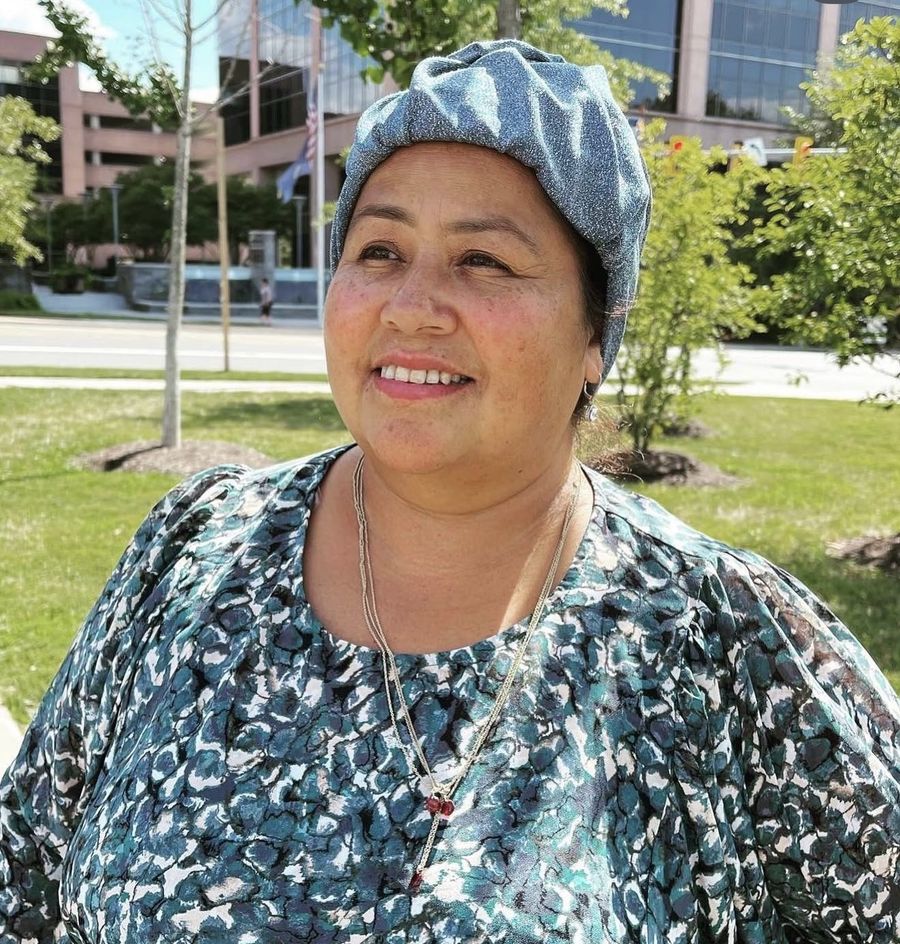 A woman smiling outdoors in a sparkly blue headwrap
