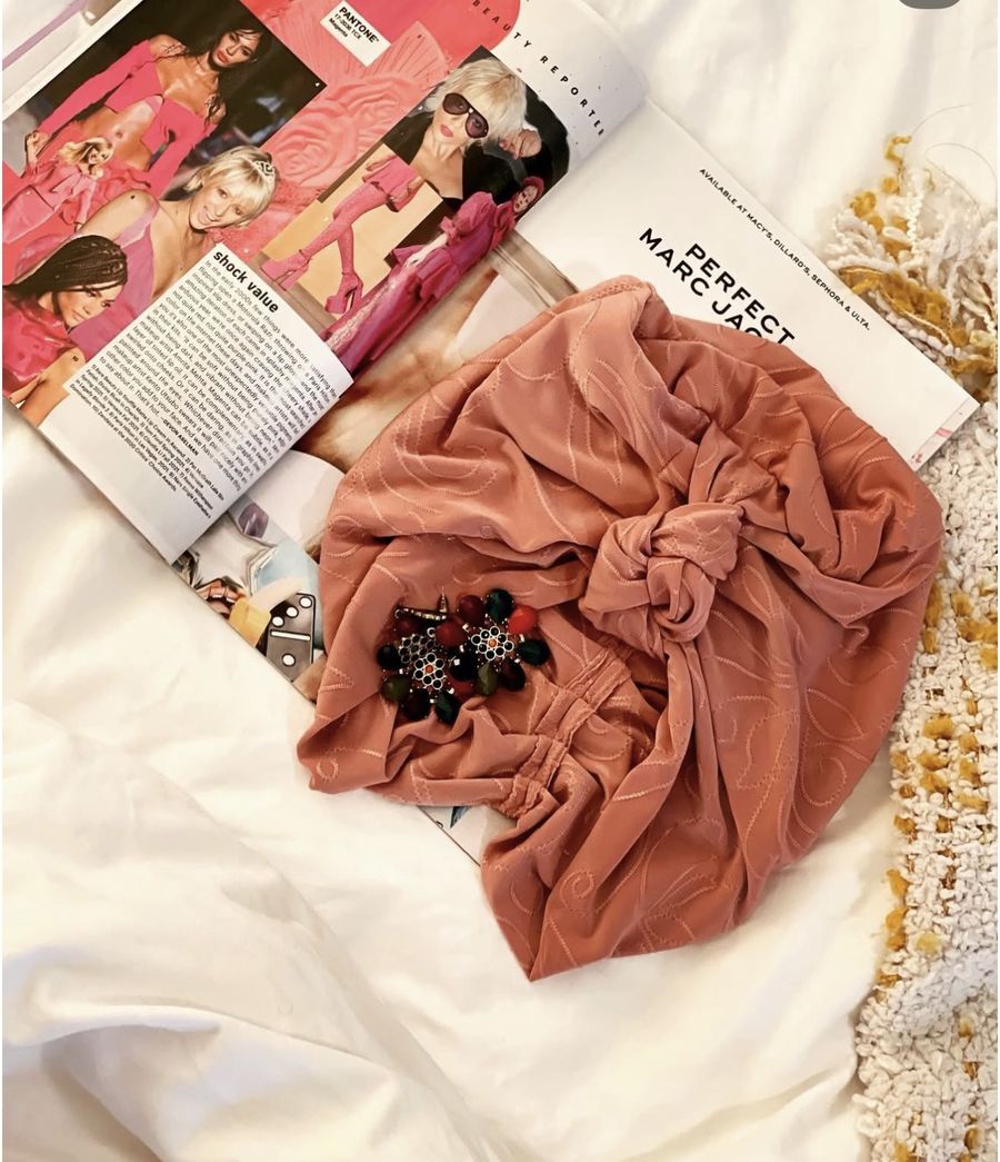 A rose headwrap with jeweled earrings on a magazine